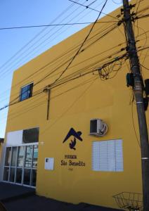 un bâtiment jaune avec un panneau sur son côté dans l'établissement Pousada São Benedito, à Cachoeira Paulista