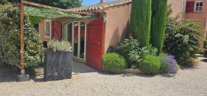 einen Garten mit einer roten Tür und einigen Pflanzen in der Unterkunft Appartement à La Bastidonne in La Bastidonne