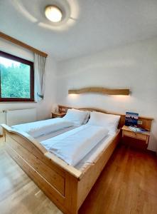 a bedroom with a large wooden bed and a window at Appartements Lärchenhof in Bad Kleinkirchheim