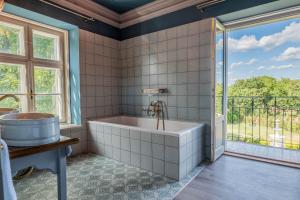 a bathroom with a tub and a window at Kaštieľ Nána in Nána