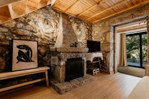 a living room with a stone wall with a fireplace at Red Fox Lodge Serra da Estrela in Eirô