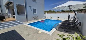 a swimming pool with an umbrella and two chairs and a table and an umbrella at Apartment Alicia with private pool in Vodice