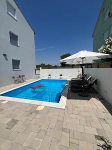 a swimming pool with an umbrella and a table and chairs at Apartment Alicia with private pool in Vodice