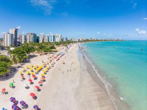 une plage avec des parasols et des gens dans l'eau dans l'établissement Apartamento em Maceió, à Maceió