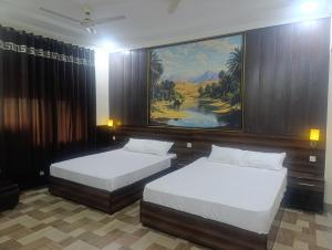 a bedroom with two beds and a painting on the wall at Bin-Umar Guest House chakswari in Burotiān +30 photos