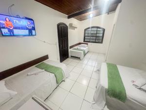 a room with two beds and a tv on the wall at Pousada Villa das Palmeiras in Búzios +35 photos