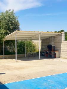 Un pabellón blanco con una mesa de picnic y una piscina. en Villa Alarilla Grupos Grandes, en Fuentidueña de Tajo