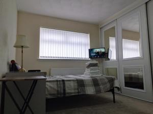a bedroom with a bed with a table and a tv at Studio Twenty One in Whitburn