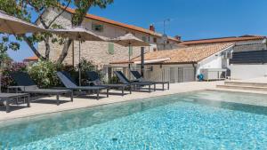 a pool with chairs and umbrellas next to a house at Villa Verde Višnjan in Višnjan