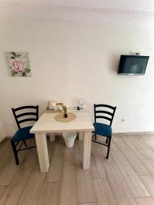 a white table with two chairs and a tv on a wall at Guest house Ema in Grabovac