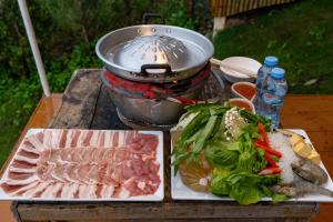 a table with meat and vegetables and a pot at บ้านละอองฟ้า1 แอร์ ม่อนแจ่ม วิวดอยหลวงเชียงดาว in Mon Jam +12 photos