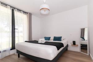 a white bedroom with a large bed with blue pillows at Arz - 2 pièces neuf proche gare de Vannes in Vannes