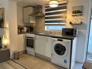 a kitchen with a washing machine and a washer at Watford Junction, King Size Bed in Watford