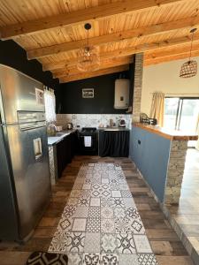 a kitchen with a stainless steel refrigerator and wooden ceilings at El Cardo in General Belgrano