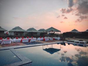 斋沙默尔Lakhmana Desert Camp With Swimming Pool的一个带桌椅的游泳池的度假酒店