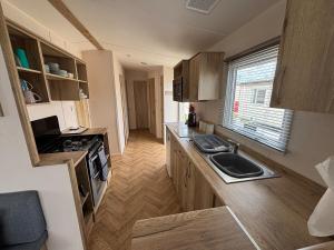 eine kleine Küche mit Spüle und Herd in der Unterkunft Palm Grove 118 - Golden Palm Resort - pet friendly, Wi-Fic close to the beach - Meadow Lakes Caravan & Lodge Hire in Chapel Saint Leonards + 3 Fotos