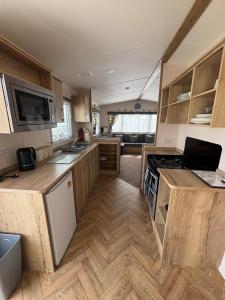 eine Küche mit Holzschränken und einem Herd mit Backofen in der Unterkunft Palm Grove 118 - Golden Palm Resort - pet friendly, Wi-Fic close to the beach - Meadow Lakes Caravan & Lodge Hire in Chapel Saint Leonards