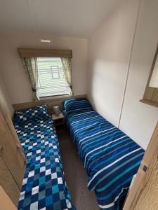 zwei Betten in einem kleinen Zimmer mit Fenster in der Unterkunft Palm Grove 118 - Golden Palm Resort - pet friendly, Wi-Fic close to the beach - Meadow Lakes Caravan & Lodge Hire in Chapel Saint Leonards