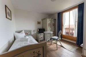 a bedroom with a bed and a table and a window at Ferienwohnungen Chiemgau in Rottau