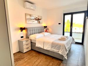 sypialnia z łóżkiem i dużym oknem w obiekcie Apartments Jovic Opatija w mieście Ičići