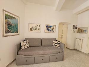 a couch in a living room with paintings on the wall at Appartamento Cà dii Cici - Da Carlutin in Riomaggiore