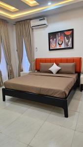 a bed with an orange headboard in a bedroom at Mdcubehomesandproperties 