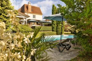 a patio with a table and an umbrella next to a pool at Logis Hôtel-Restaurant Les Voyageurs in La Coquille