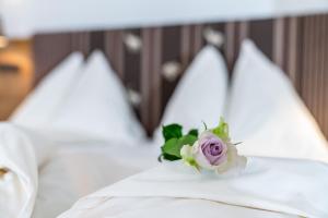 kwiat na łóżku z białymi poduszkami w obiekcie Aktivhotel Pehab w mieście Ramsau am Dachstein