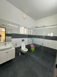 a bathroom with a toilet and a sink and a shower at Cozy Homestays in Ernakulam