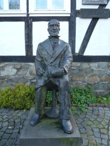 une statue d'un homme assis sur un banc dans l'établissement Gasthof Kettler, à Assinghausen