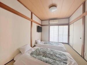 two beds in a room with a window at 海の小石 in Ito