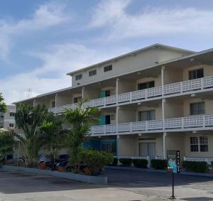 an apartment building with white balconies and palm trees at Melrose Beach Apartments Inc in Bridgetown