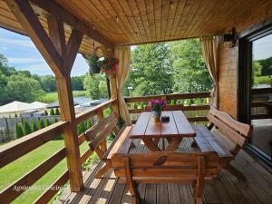 a wooden deck with a wooden table and two benches at Relax przy plaży in Wilnowo
