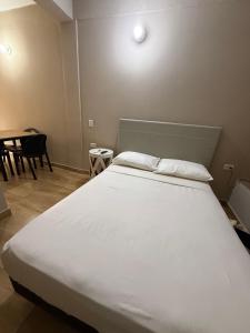 a bedroom with a large white bed and a table at Departamento Bita in Puerto Iguazú