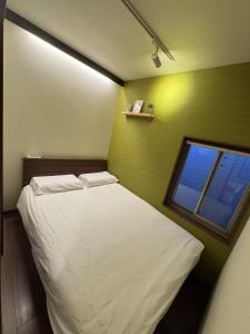 a small bedroom with a white bed and a window at Tokyo Skytree House 4LDK, 2Bath, 9 Guests, 6min to Keisei Hikifune in Tokyo