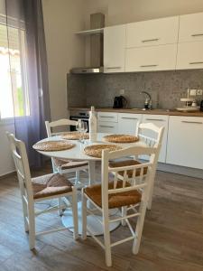 a kitchen with a white table with chairs and a tableasteryasteryasteryasteryastery at La mer in Moúdhros