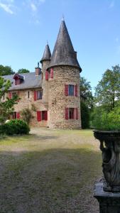 ein altes Steinhaus mit roten Rollläden auf einem Hof in der Unterkunft Chateau de Bellefond in Lagraulière