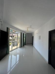 an empty room with white walls and large windows at Samriddhi Homestay in Trivandrum
