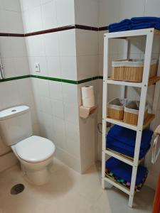 a bathroom with a toilet and a shelf with towels at Oasis en la playa de Albir Apartamento in Albir