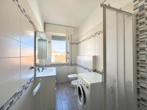 a white bathroom with a toilet and a sink at Armellini, vicino al mare con aria condizionata By Alfareal in Castiglione della Pescaia +14 photos