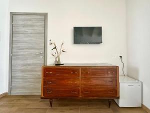 a room with a wooden dresser with a television on the wall at Austinu e Bingedda's Home in Ardara