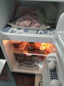 an open refrigerator filled with food and a chicken at Estúdio Bambuzal no Centro in Alto Paraíso de Goiás