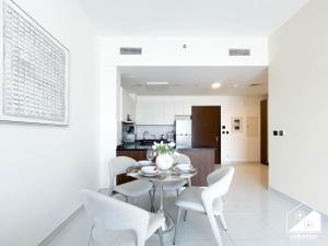a white kitchen and dining room with a table and chairs at Bright 2Bed Family Home l Pool , Gym access in Dubai