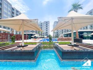 a swimming pool with two umbrellas and a pool at Bright 2Bed Family Home l Pool , Gym access in Dubai