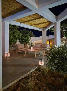 a patio with two chairs and a bench under a pavilion at Liakoto Villa with private pool and jacuzzi in Makry Gialos