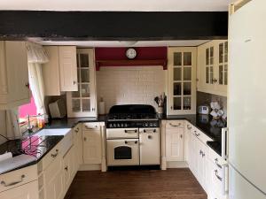 a kitchen with white cabinets and a stove top oven at The Linney in Teigngrace