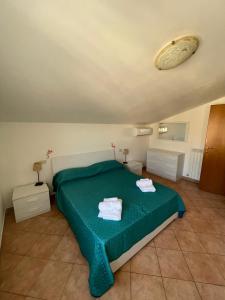 a bedroom with a green bed with towels on it at Verdemare Apartments in Fano