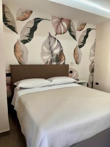 una camera da letto con un letto grande con una parete con foglie di Casa Historical Center a Napoli