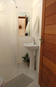 un bagno bianco con lavandino e specchio di Suíte Alvorada Tiradentes MG a Tiradentes