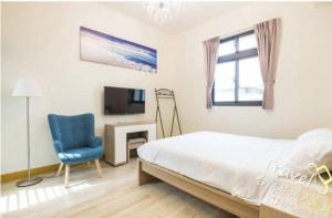a bedroom with a bed and a blue chair and a television at 東華晴空樹民宿 in Shoufeng